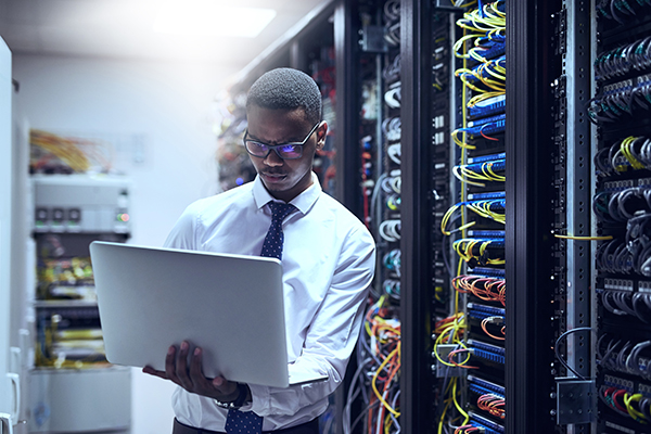 Image of man on a laptop in a server room