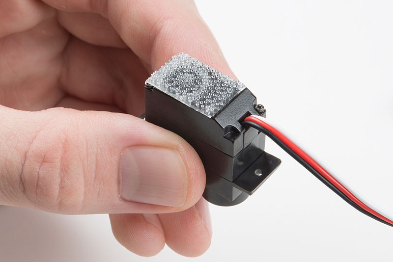 Peel off adhesive/stick one half on bottom of servo